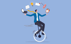Illustration of a man on a unicycle juggling a laptop, alarm clock a target and other work-related symbology