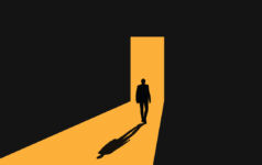 A shadowy figure approaches the light of a doorway