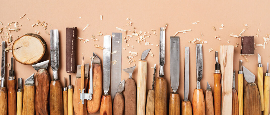 Carpentry workshop desk with set of different handmade carving tools for working with wood top view.
