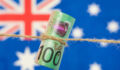 Close up of an Australian one hundred dollar bill tied in string. Australian flag in background.