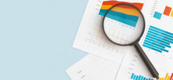 A magnifying glass lies on top of several documents of infographics
