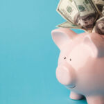 A pink piggy bank stuffed with dollar bills