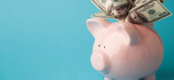 A pink piggy bank stuffed with dollar bills