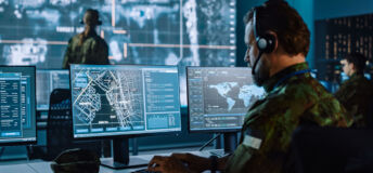 A military command and communications centre with operatives looking at urban maps on computer screens