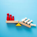 Wooden figures on a shelf, half of whom are falling off