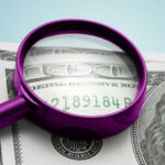 magnifying glass looks at serial no of a $100 bill