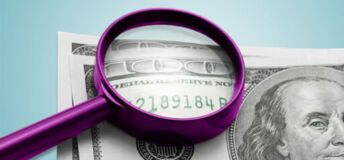 magnifying glass looks at serial no of a $100 bill