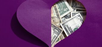 A love-heart shaped hole in a piece of people reveals US dollars underneath