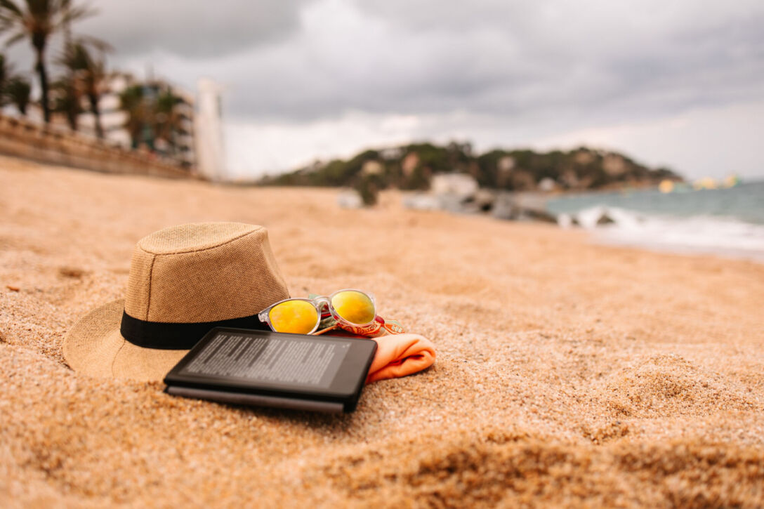 Beach accessories - hat, towel, sunglasses and e-reader on the beach