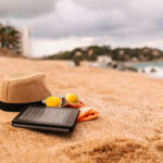 Beach accessories - hat, towel, sunglasses and e-reader on the beach