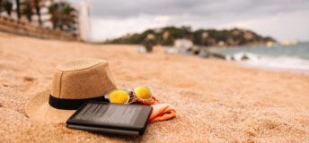 Beach accessories - hat, towel, sunglasses and e-reader on the beach