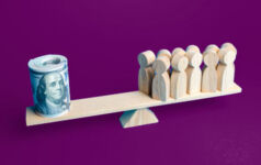 tiny see saw with a roll of dollar bills balancing wooden chess-type pawns