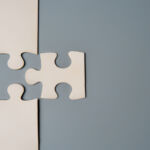 Number Crunch: Private equity M&A remains a big deal Two puzzle pieces connecting, one white and one grey, on a contrasting background